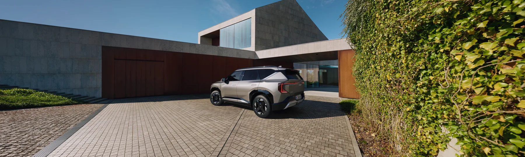 Kia EV5 in der Heckansicht vor einem Landhaus