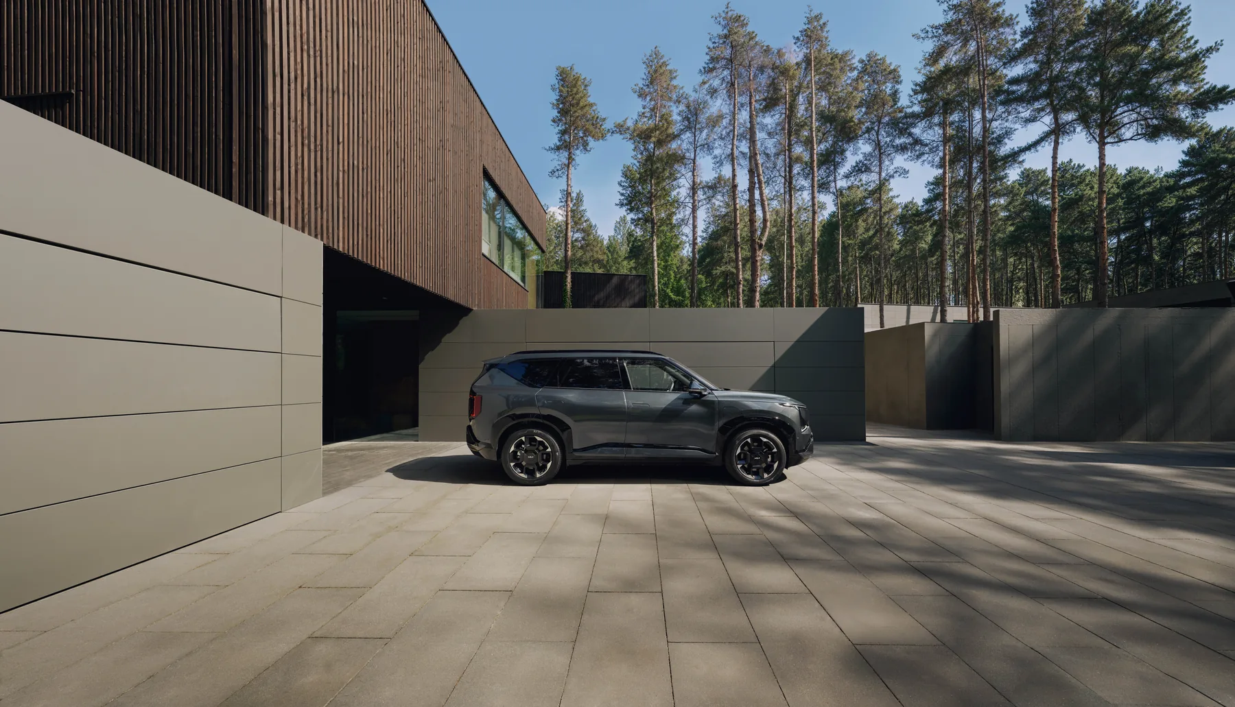 Kia EV5 GT-line in der vollen Seitenansicht vor einem Waldhaus
