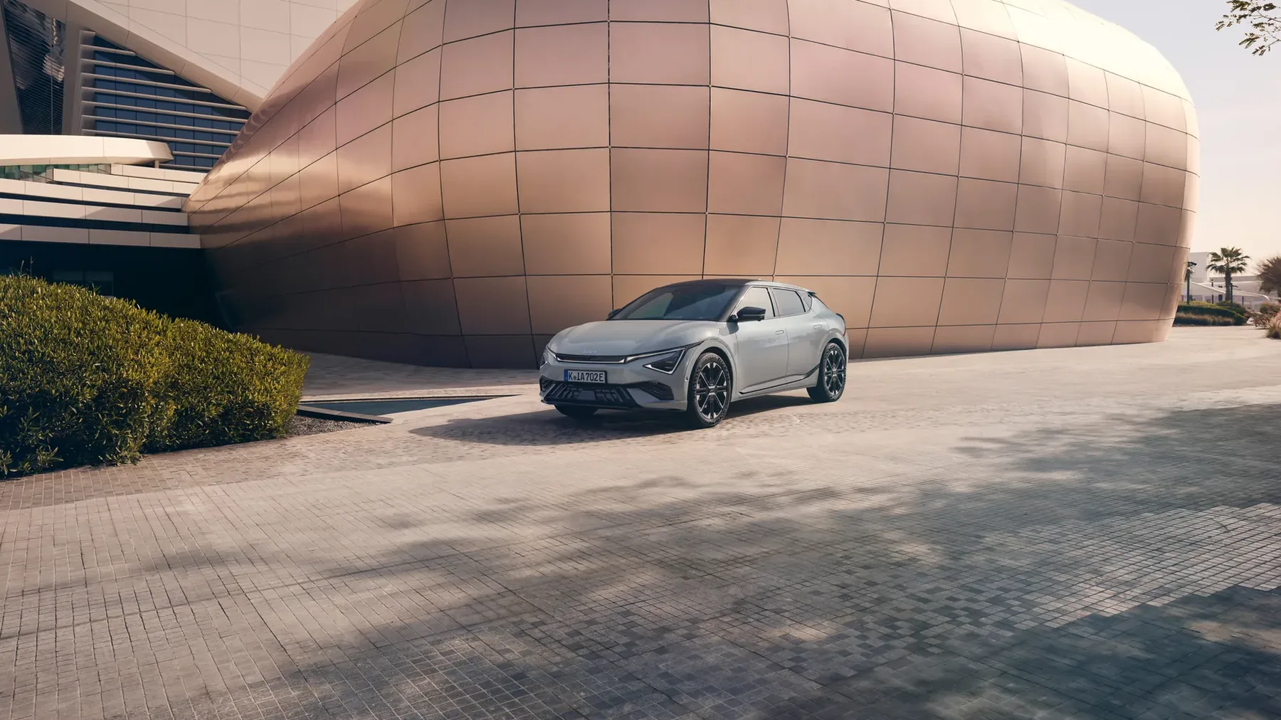 Kia EV6 in Silber vor einem geschwungenen Gebäude