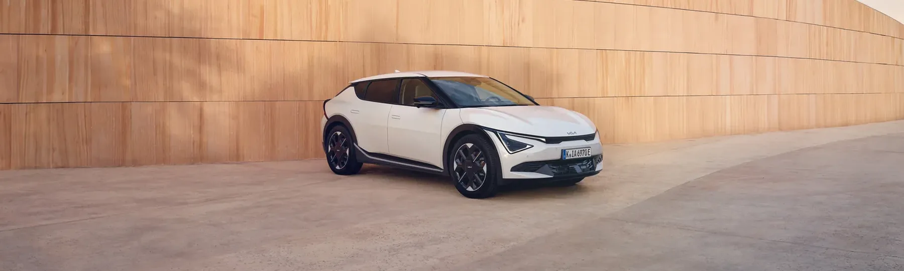 Kia EV6 in Weiß in der Seitenansicht vor einer Holzfassade