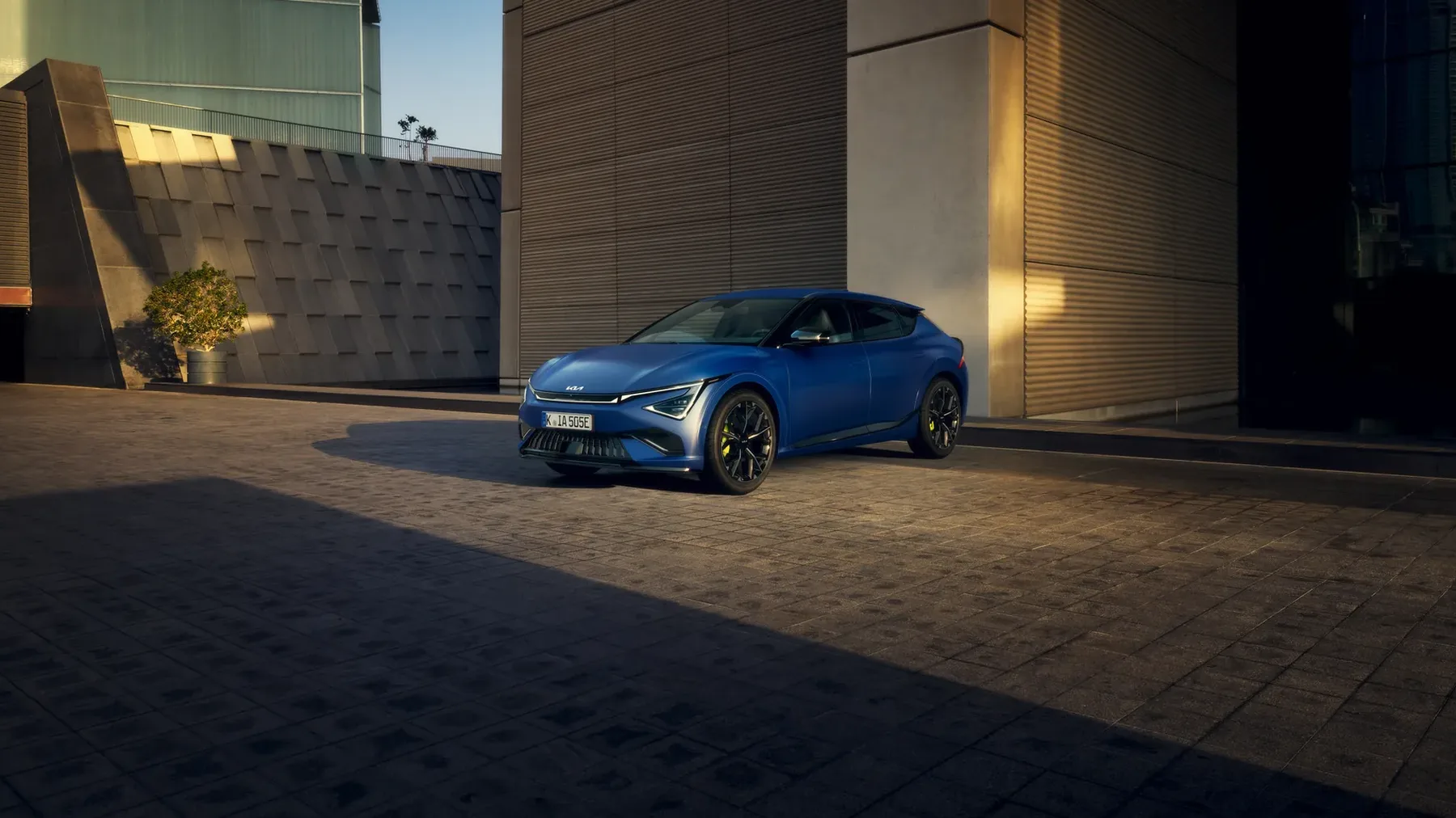 Kia EV6 GT in Blau vor einer Betonfassade, Dreiviertelansicht von vorn