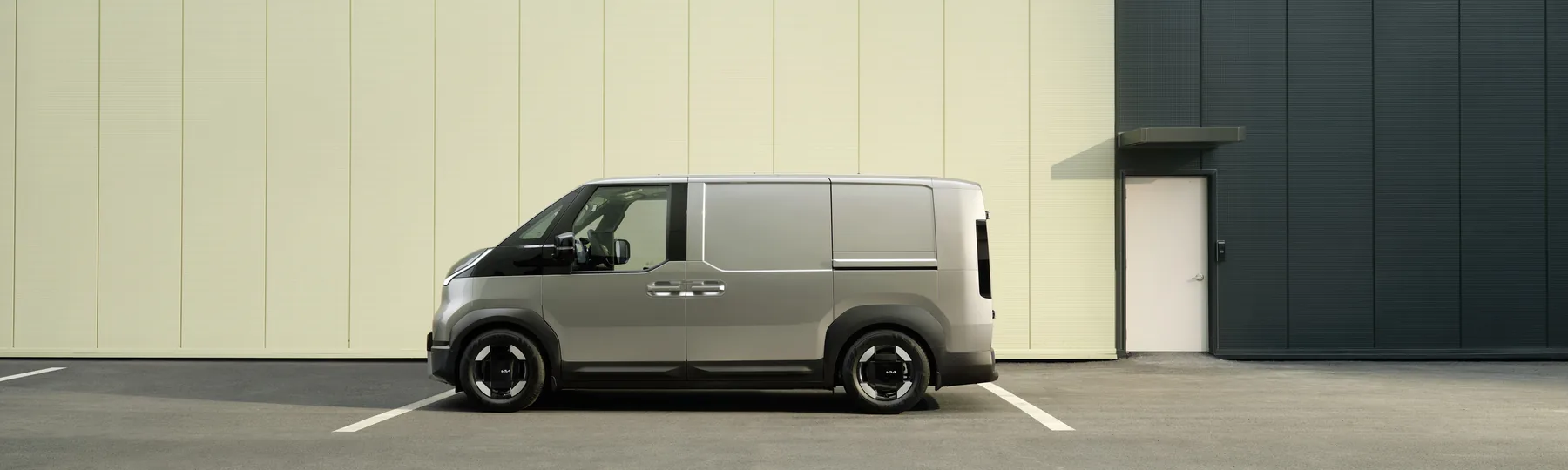 Kia PV5 Cargo in der Seitenansicht vor einer Lagerhalle