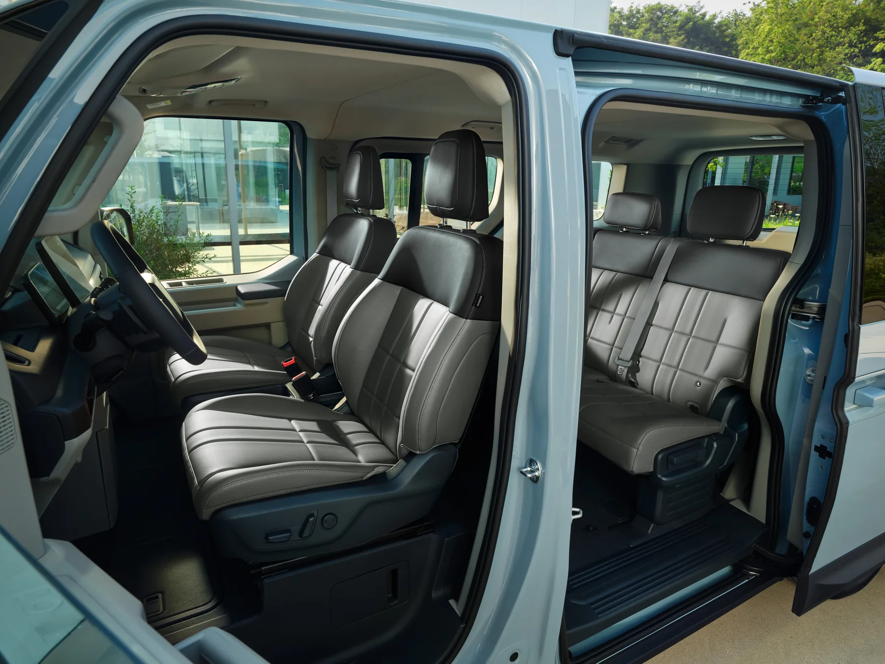 Blick durch die geöffnete Schiebetür auf die Sitzreihen des Kia PV5 Passenger